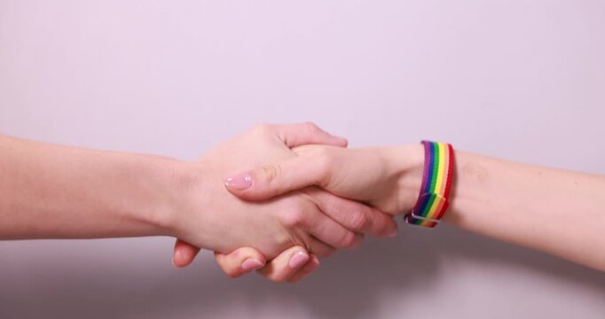 LGBT concept. Women shaking hands on light background, closeup