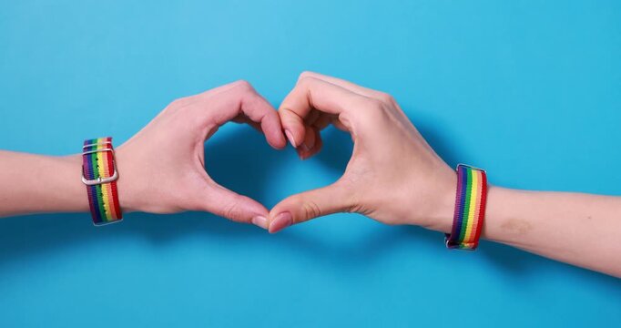 LGBT concept. Women making heart of hands on light blue background, closeup