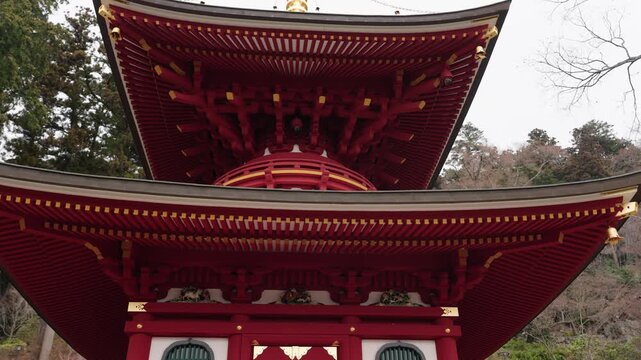 Low angle close view of ornate red lacquer pagoda roof with gold spire and bracket details at Katsuoji