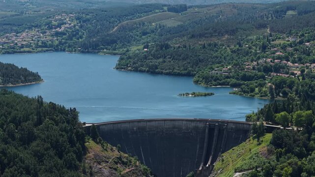 aerial - Concrete arch dam retaining Cani&ccedil;ada reservoir surrounded by forested hills in Ger&ecirc;s Portugal
