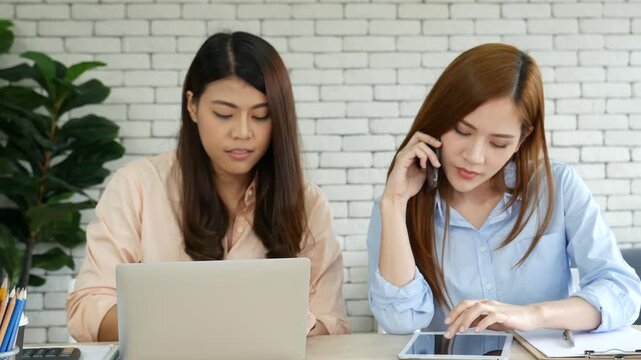 Two woman work at home office meeting team discuss using laptop financial graph chart in office desk. Two young woman reading Planning analyze marketing. freelance Partners team happy workspace