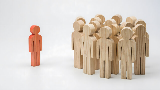 A single orange wooden figure standing apart from a group of wooden people