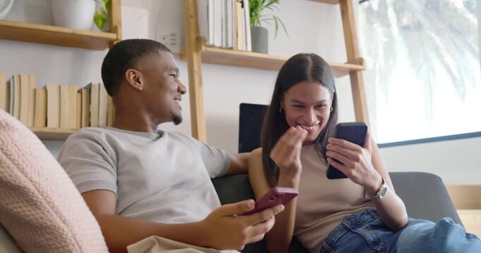 African American couple sitting on couch, woman showing phone, man comparing phones while listening