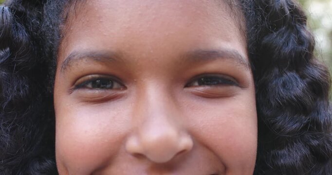 Camera pulling back, African American female youth smiling, shifting head outside, engaging viewer