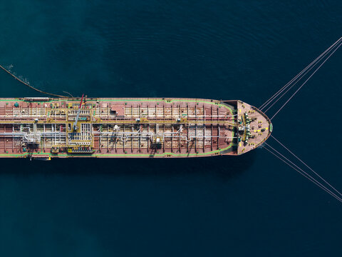 Aerial view of an oil tanker ship moored at the Oil Fuel Terminal Port, with pipelines and deck structures visible on the calm blue sea in Manggis, Bali, Indonesia.