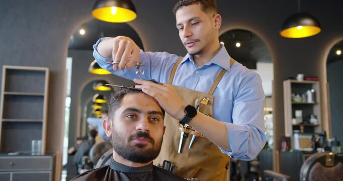 African American barber checking hair at barbershop using comb and scissors shaping front hairline