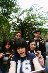 Fototapeta premium Group of young Hispanic university students playing mobile video games together outdoors in Mexico City