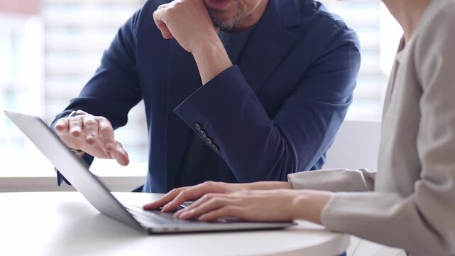 ビジネスウーマンにパソコンを教える中高年のビジネスマン