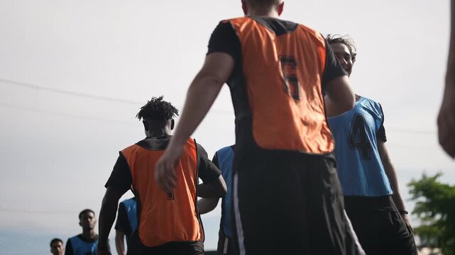 Two teams of young footballers walk up and shake hands before practicing their football skills or before the start of a game on the outdoor football field. Football teams train and compete on outdoor 