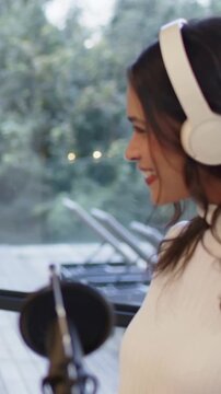 Vertical video: Entering right, host at mic at home, recording in white top and headset, copy space