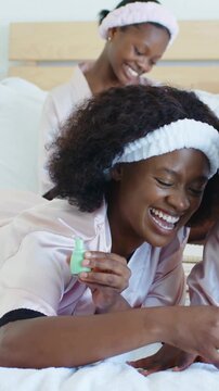 Vertical video: Laughing mom dipping brush, painting girl's nails on bed, robe, mint bottle to bond