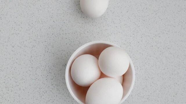 Close-up of chicken eggs in a bowl on a light background, conveying freshness and naturalness. Fresh eggs in a small bowl, highlighting clarity and simplicity on the illuminated surface.