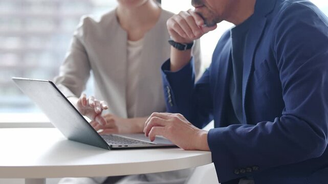 中高年のビジネスマンにパソコンを教えるビジネスウーマン