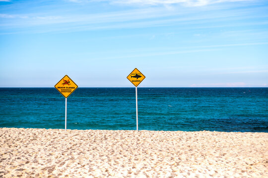 Shark warning and beach closure signs on Bronte Beach following a shark incident, with calm ocean and blue sky, Sydney, Australia.