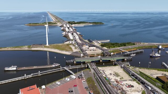 Aerial perspective of the impressive afsluitdijk causeway, showing the lorentzsluizen lock complex, highway traffic, and wind turbines generating renewable energy in the ijsselmeer