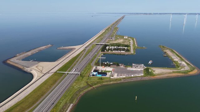 Impressive aerial shot of the afsluitdijk causeway in the netherlands, a major dam connecting north holland and friesland, with traffic flowing and wind turbines generating clean energy