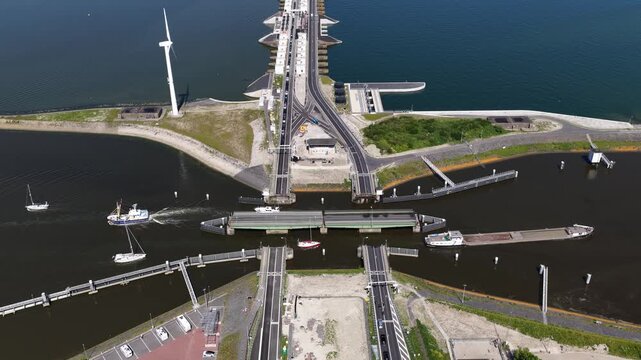 Aerial view zooming into the afsluitdijk showing open locks and bridges allowing various boats and ships to pass from the ijsselmeer to the wadden sea, a vital part of dutch water management
