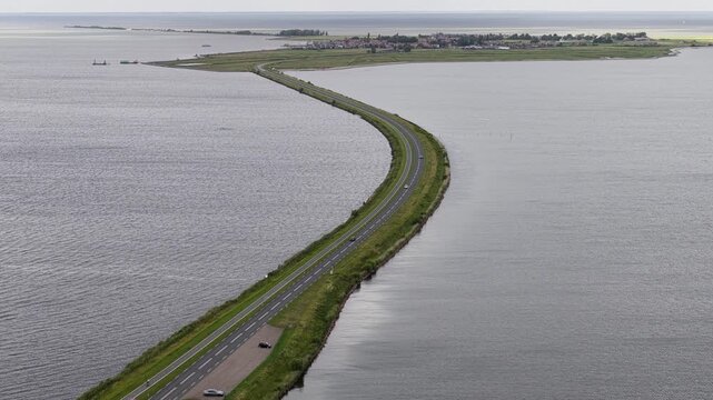 Impressive aerial shot capturing the long, winding causeway road through the markermeer, connecting the historic former island of marken to the dutch mainland, with a wind turbine visible