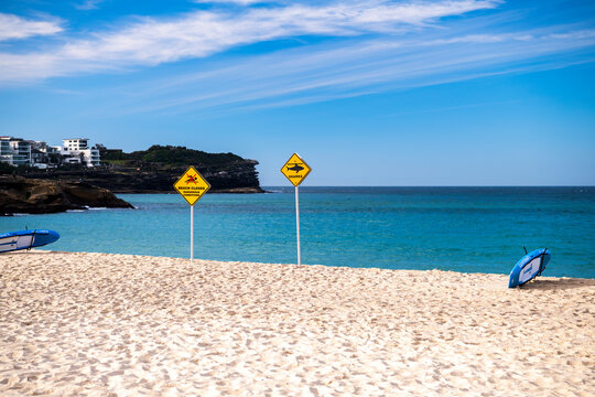 Shark warning and beach closure signs on Bronte Beach following a shark incident, with calm ocean and blue sky, Sydney, Australia.