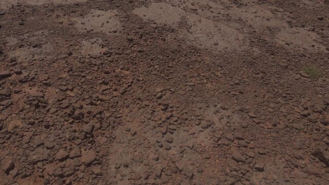 Closeup of arid rocky ground with small stones and dry soil texture in Moroccan desert terrain
