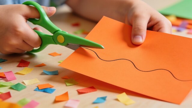 Child Cutting Orange Paper with Decorative Scissors