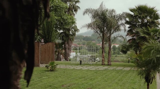 Lush garden venue with tall palm trees white lattice ceremony arch and mountain backdrop