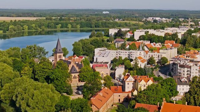 Drone moves right, Sztum revealing church tower, lakeshore, urban landscape