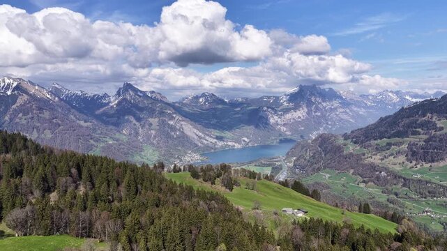 Sweeping aerial view of Walensee lake and valley town surrounded by forested slopes and snowy Swiss Alps