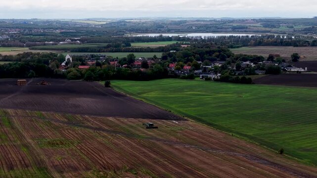 Aerial drone footage of agricultural farmland and rural countryside near Eg&aring; Denmark with cultivated fields and distant village landscape.