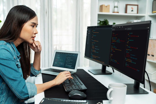 Young Asian in IT developer creating with typing online information on pc with coding program data of website application, wearing jeans shirt. surrounded by safety analysis two screens. Stratagem.