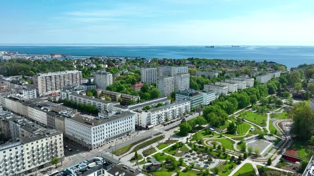 A cinematic aerial drone shot of Gdynia, Poland, showing modern architecture, lush green parks, and the blue Baltic Sea. Useful for travel, urban planning, and sustainability themes.