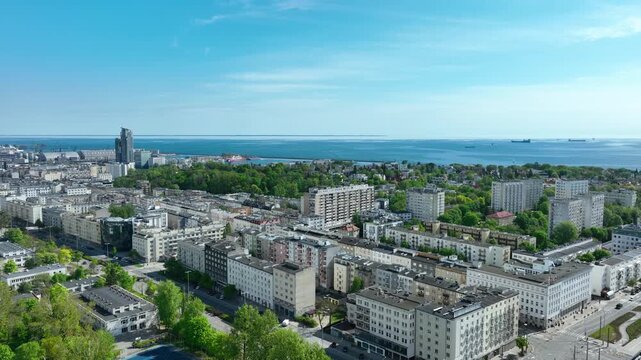 High angle aerial shot of Gdynia city center featuring residential blocks, green parks, and the Baltic Sea horizon. Suitable for travel and urban development content.
