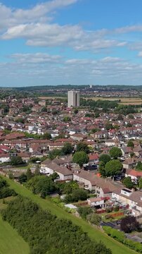 Verticaldrone flyover of Chad Park, Chadwell Heath, moving forward toward Highview House tower block near the A12, showing suburban rooftops, green space, and clouds over east London, UK.