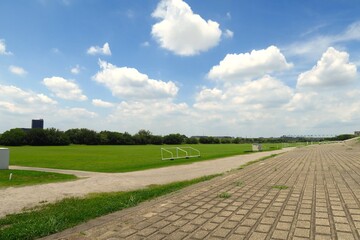 初夏の梅雨の晴れ間の江戸川土手の護岸から見るサッカー場のある江戸川河川敷風景 © smtd3
