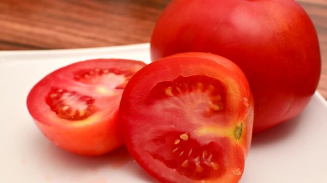 Fresh Red Tomato: Succulent slices on a white plate, ready to inspire your culinary creations. Close-up of sliced red tomatoes, an appetizing sight to awaken the taste buds.