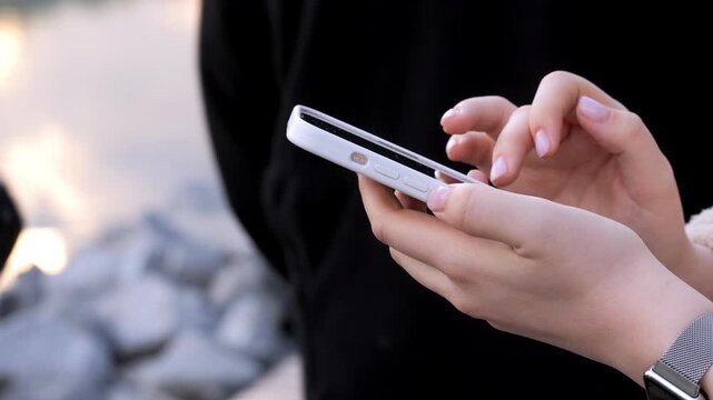 Close-up of hands holding and swiping on a smartphone. Fingers move confidently across the screen. Soft natural lighting enhances the scene. Person appears focused and relaxed while using their device