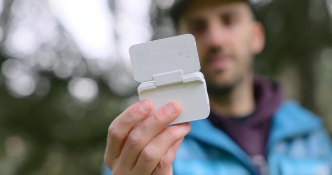 Man outdoors examining an Insta360 Go Ultra action camera, prepping a compact gadget for adventure filming.