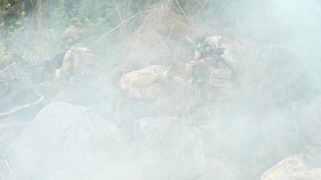 Soldiers conducting tactical maneuvers in a smoky environment surrounded by natural landscapes