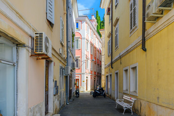 Fototapeta premium A narrow residential alley leading to a picturesque pink colored building in the coastal town of Piran, Slovenia, in the Istrian region of the Adriatic Sea.