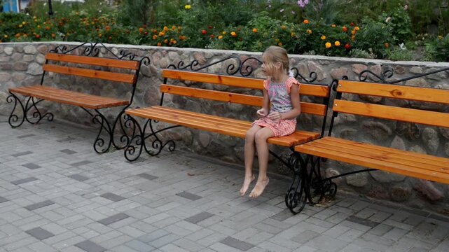 Two little girls are sitting on wooden bench