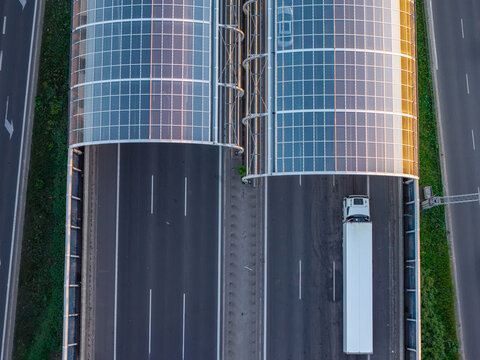 Aerial view of glass noise barriers covering a highway with a white truck driving through in Warsaw, Masovian Voivodeship, Poland.