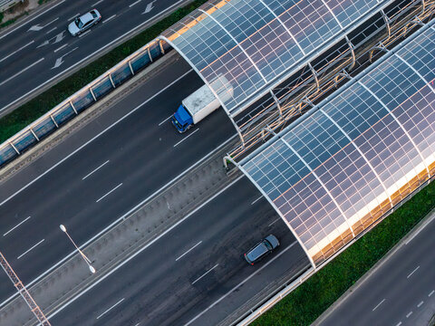 Aerial view of glass noise barriers with solar panels installed over a highway with moving vehicles in Warszawa, Mazowieckie, Poland.