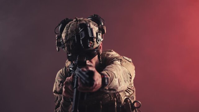 Military operator in camouflage tactical uniform carrying an assault rifle, isolated background. Concept defense forces, security and combat equipment.
