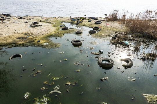 Aerial view of Lake Varna shoreline polluted with discarded tires and debris in Varna, Bulgaria.