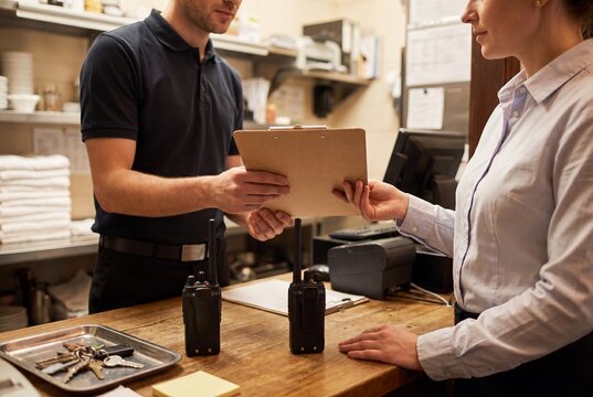 Delivery Courier Handing a Clipboard to a Restaurant Manager at the Service Counter