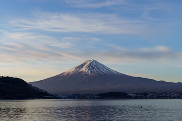 Fototapeta premium Majestic morning view of Mount Fuji under a beautiful wispy cloud sky over Lake Kawaguchi in February, with ample copy space for design, Yamanashi, Japan.