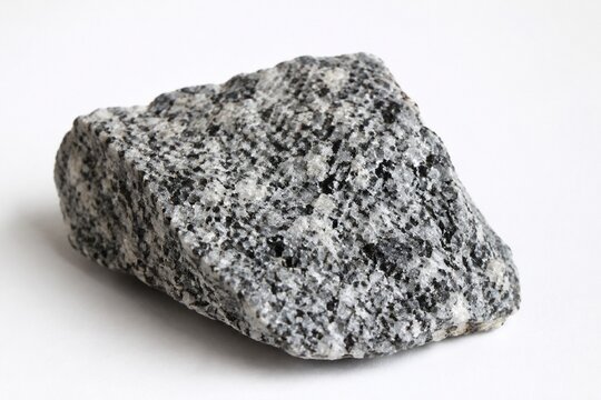 Rough diorite rock sample on white surface, natural stone texture.