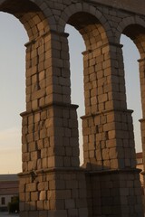 Obraz premium Weathered stone arches stand sentinel amidst the rustic charm of an ancient Roman aqueduct in Castile-León, Spain.