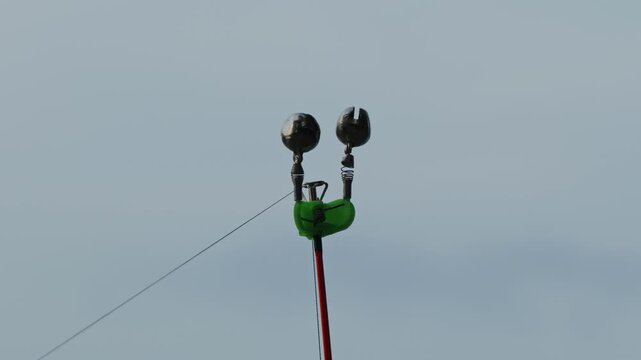 Green bite alarm bells attached to fishing rod tip close-up.