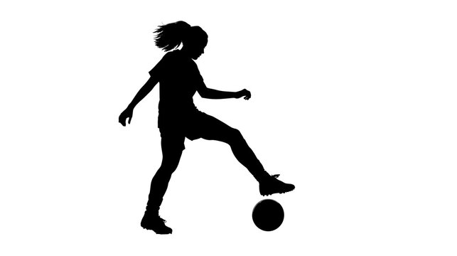 Silhouette shows a female soccer player kicking a ball